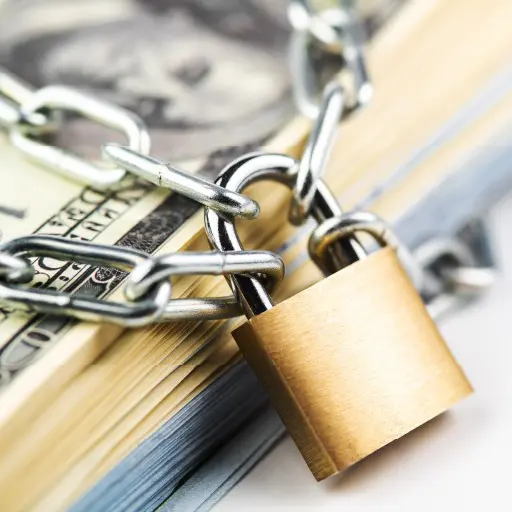 A lock and chain securing a stack of cash.