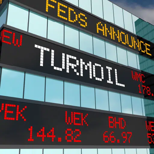 Image of stock tickers on a building with the term ‘Turmoil’ in large letters. This is meant to indicate the article is about a history of economic turmoil in the U.S.
