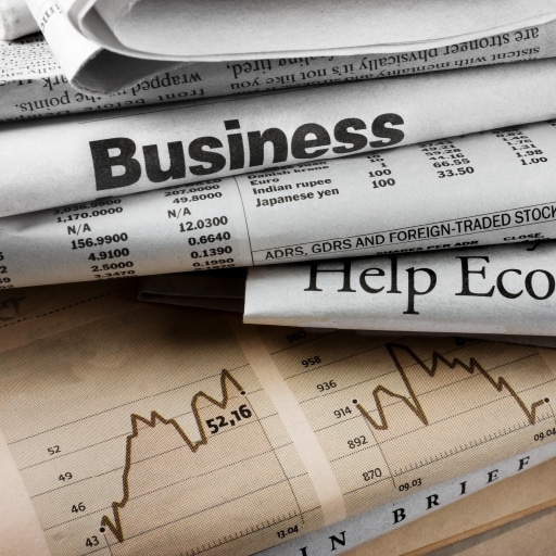 A stack of newspapers with charts and the words “help economy”. This is meant to represent a changing economy and interest rates.