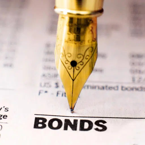 A gold pen pointing at the word bonds on a newspaper meant to represent the management of referendum funds by municipalities.