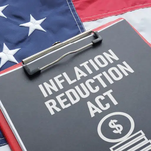 Inflation Reduction Act written on a clipboard that is sitting on an American flag.