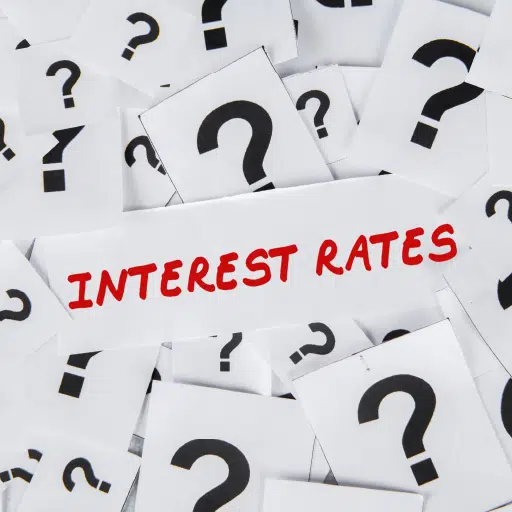 Interest Rates written on a piece of paper with the question marks laying all around it representing the question of when will interest rates go up.