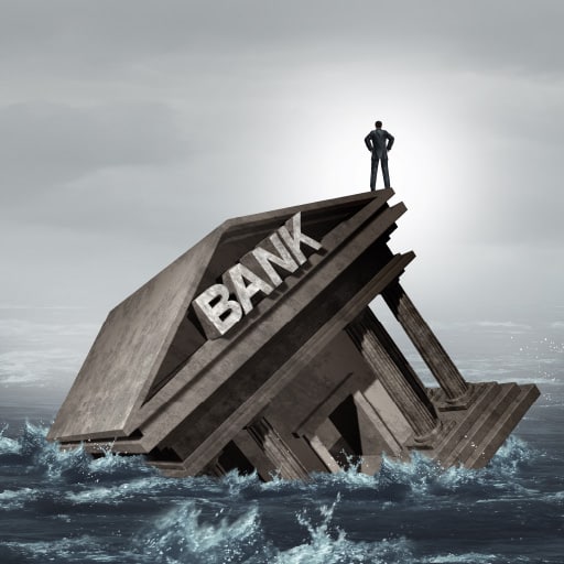 Bank failure and the need to protect business deposits is depicted by a businessman standing on a bank that’s sinking into water.