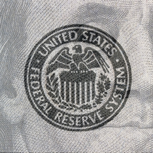 A close up of the Federal Reserve System logo stamped on a 100-dollar bill.
