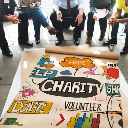 A nonprofit organization sitting around a poster with the words, donate, charity and volunteer displayed.