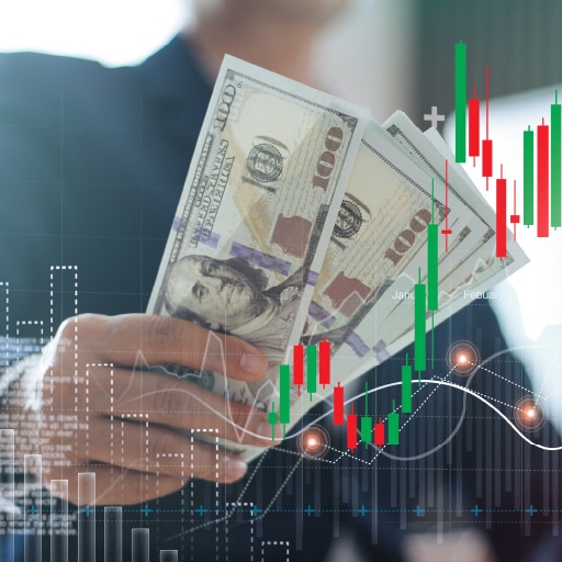 A businessperson holding U.S. 100 dollar bills overlayed with a candlestick chart – the image is meant to indicate that technology is changing cash flow management for business.