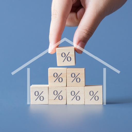 The relationship between interest rates and mortgage rates represented by cubes with percent signs inside the outline of a property.